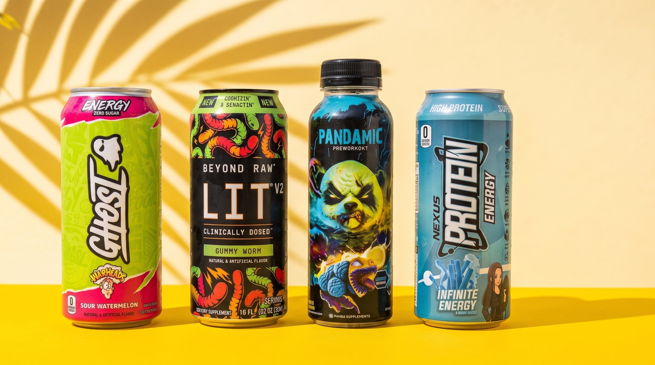 Four energy drinks lined up on a bright yellow surface in front of a palm leaf shadow